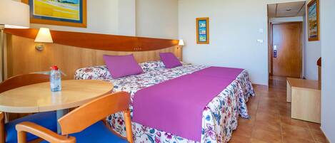 A hotel room with a bed, a table, chairs, and a small desk.