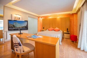 A hotel room with a bed, a desk with a chair, a television, and a red ottoman. - Hotel Servigroup Nereo (Benidorm)