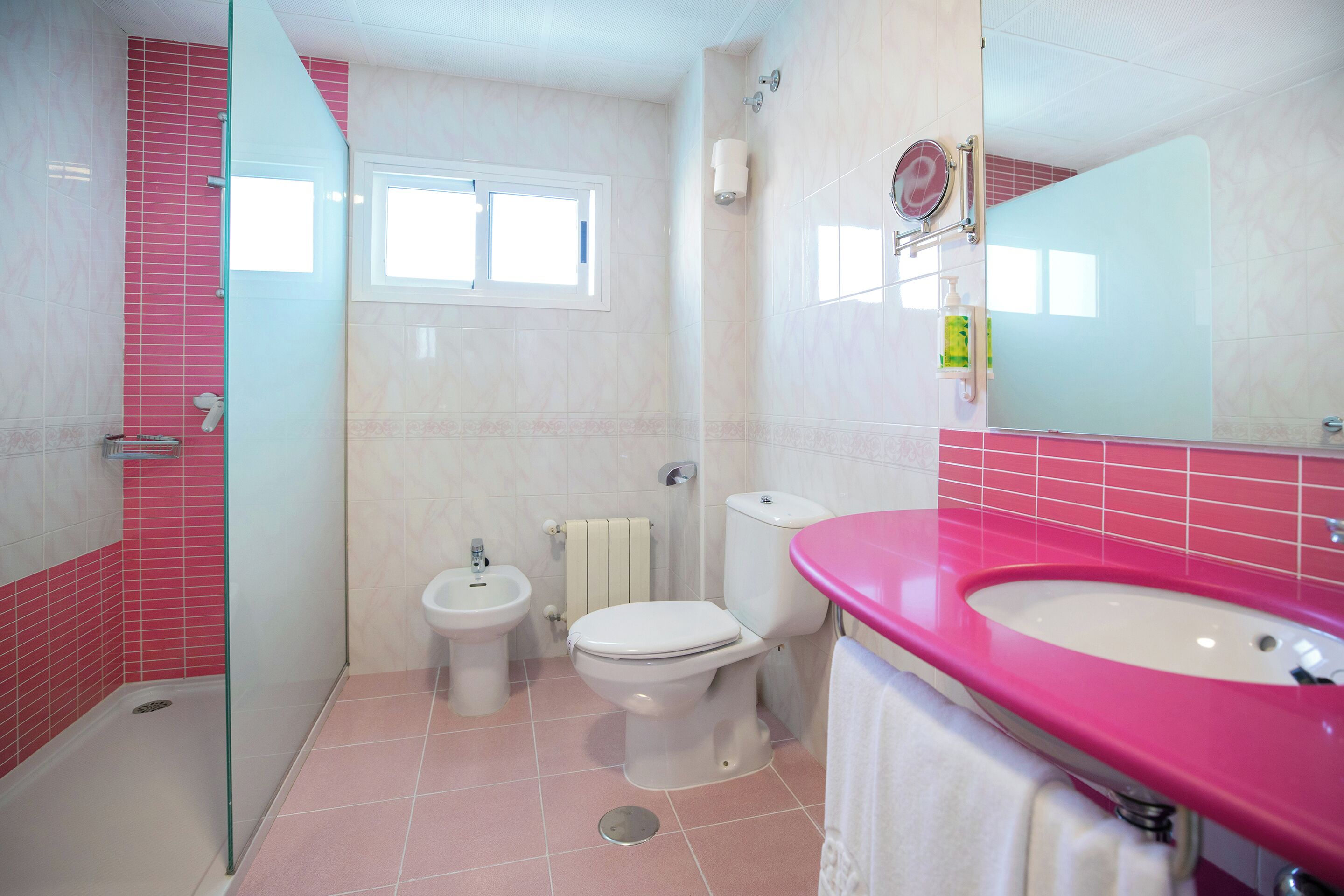 A bathroom with a shower, toilet, bidet, and sink.