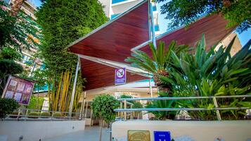 A hotel entrance with a covered walkway, a sign indicating no smoking, and a mosaic wall.
