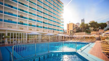 A hotel with a large indoor swimming pool, multiple balconies, and outdoor seating areas.