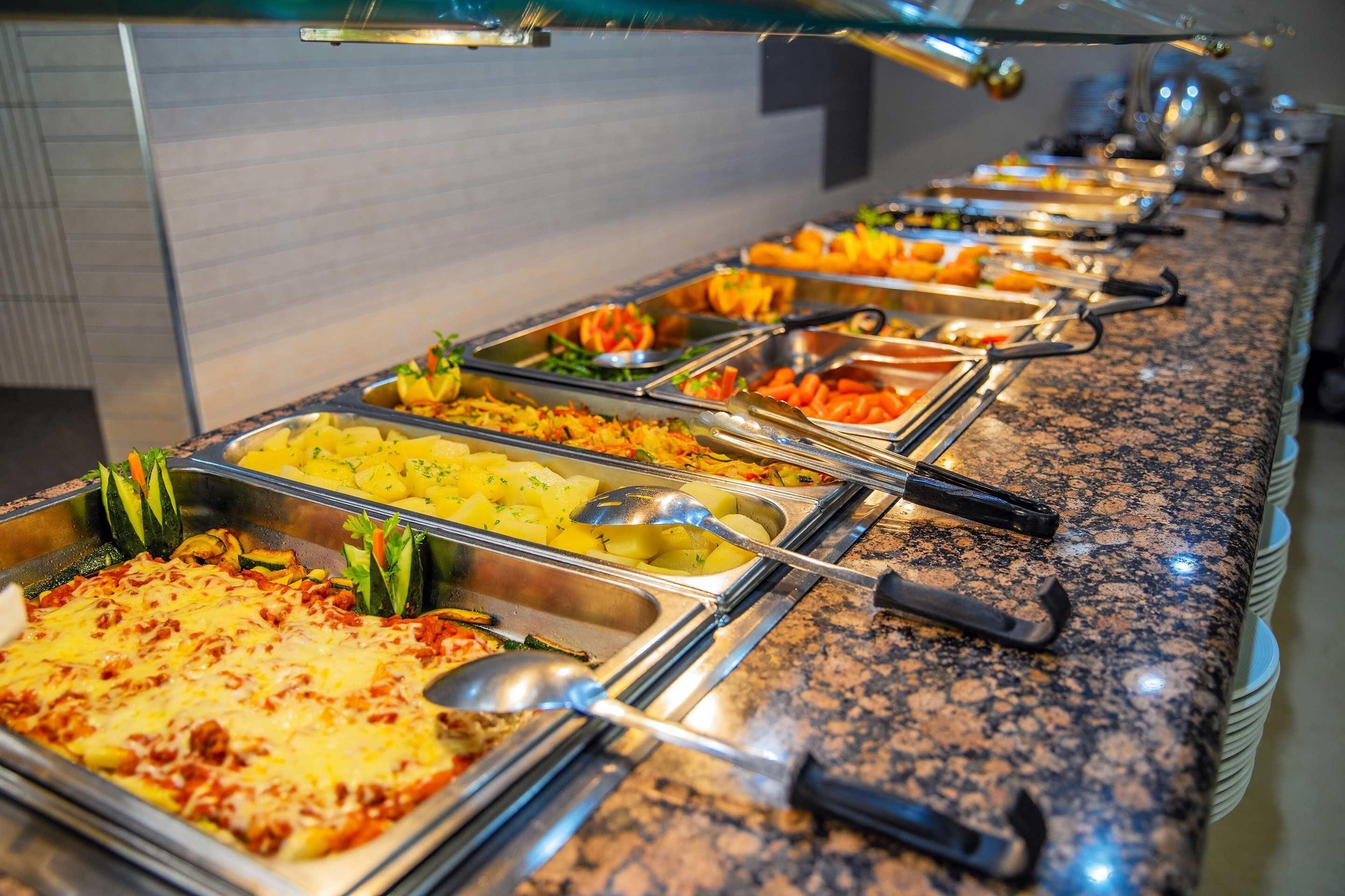 A buffet with various dishes including pasta, salads, and a casserole.