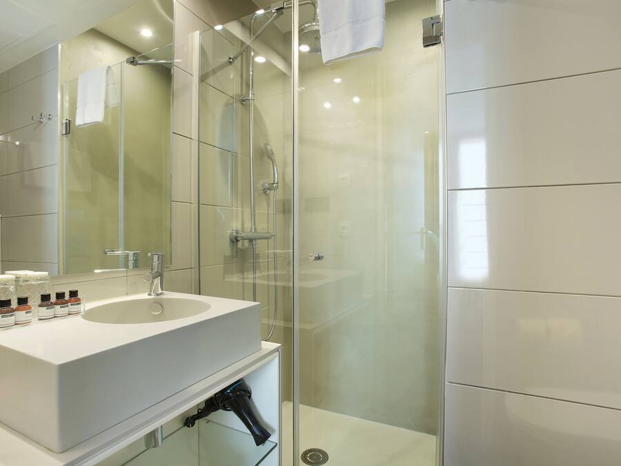 Un baño moderno con ducha envuelta en vidrio, un lavabo blanco y un espejo.