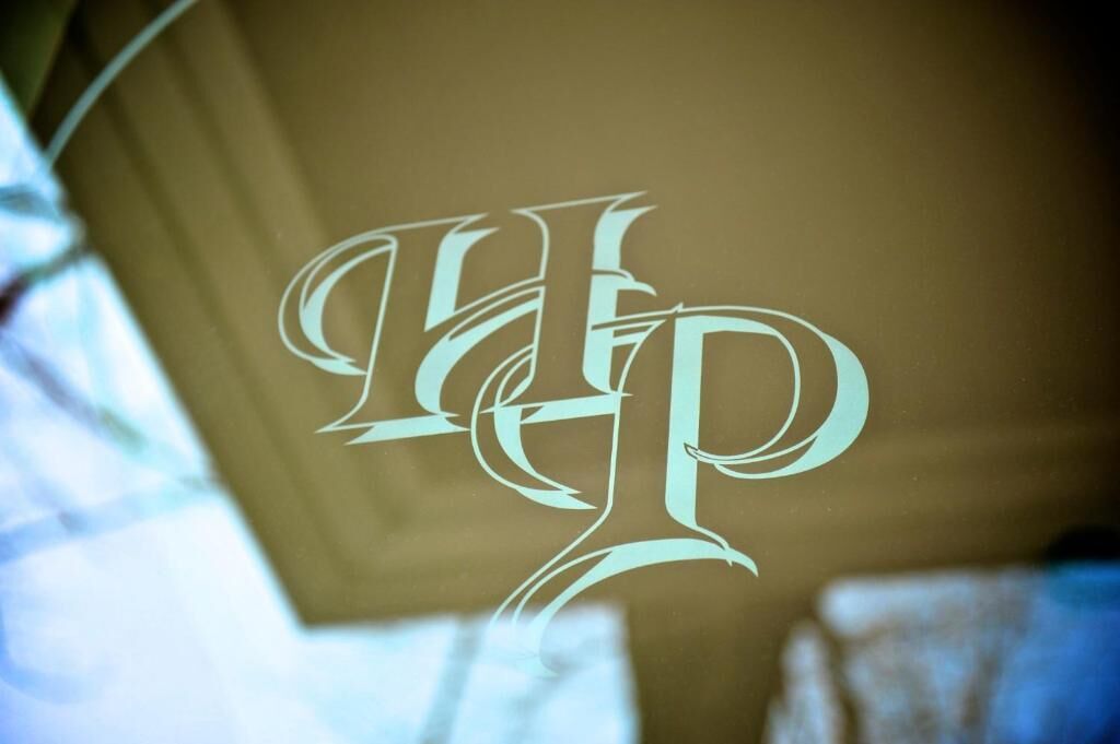 Un logo stilizzato a monogramma su una superficie di vetro.