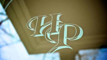 Un logo stilizzato a monogramma su una superficie di vetro.