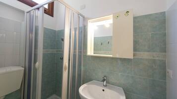 Un baño con ducha, lavabo y espejo.