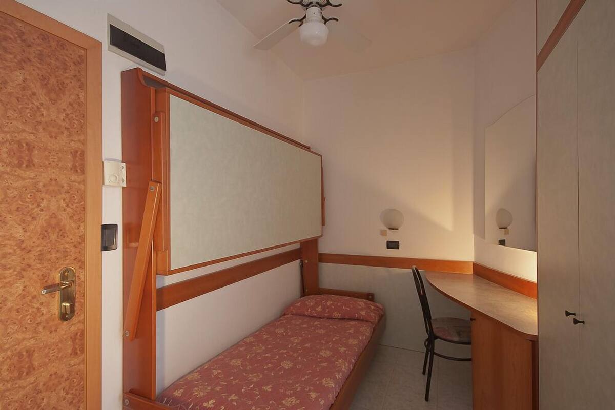 A compact room with a bunk bed, a desk, and a chair.
