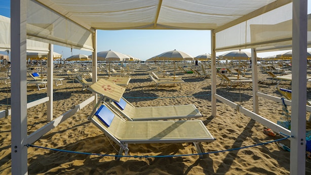 A beach with sunbeds and umbrellas under a canopy structure. - Hotel Dasamo - Dada Hotels (Rimini)