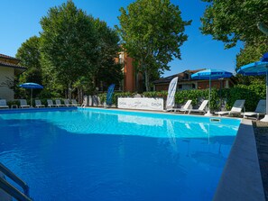 Una piscina al aire libre, sombrillas, tumbonas