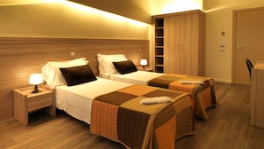 A hotel room with two beds, wooden headboards, a wardrobe, and a desk with a chair. - Hotel Villa Lalla (Rimini)
