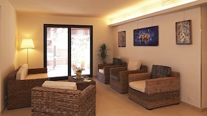 A living room with wicker furniture, a lamp, and artwork on the wall. - Hotel Villa Lalla (Rimini)