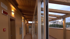 A corridor with wooden ceiling beams, tiled floor, and glass doors leading to rooms. - Hotel Villa Lalla (Rimini)