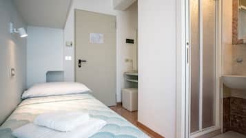 Una camera da letto con un letto, un bagno con doccia e un ingresso che dà su un corridoio.