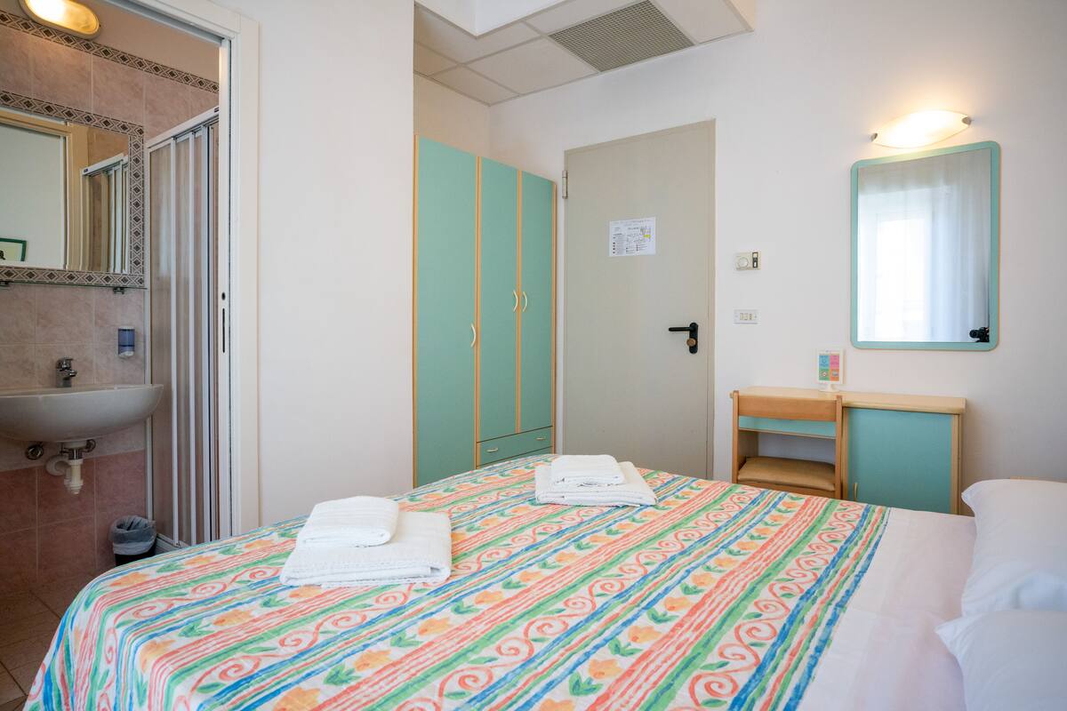 A hotel room with a bed, a bathroom with a sink, and a mirror.