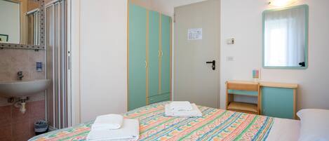 A hotel room with a bed, a bathroom with a sink, and a mirror.