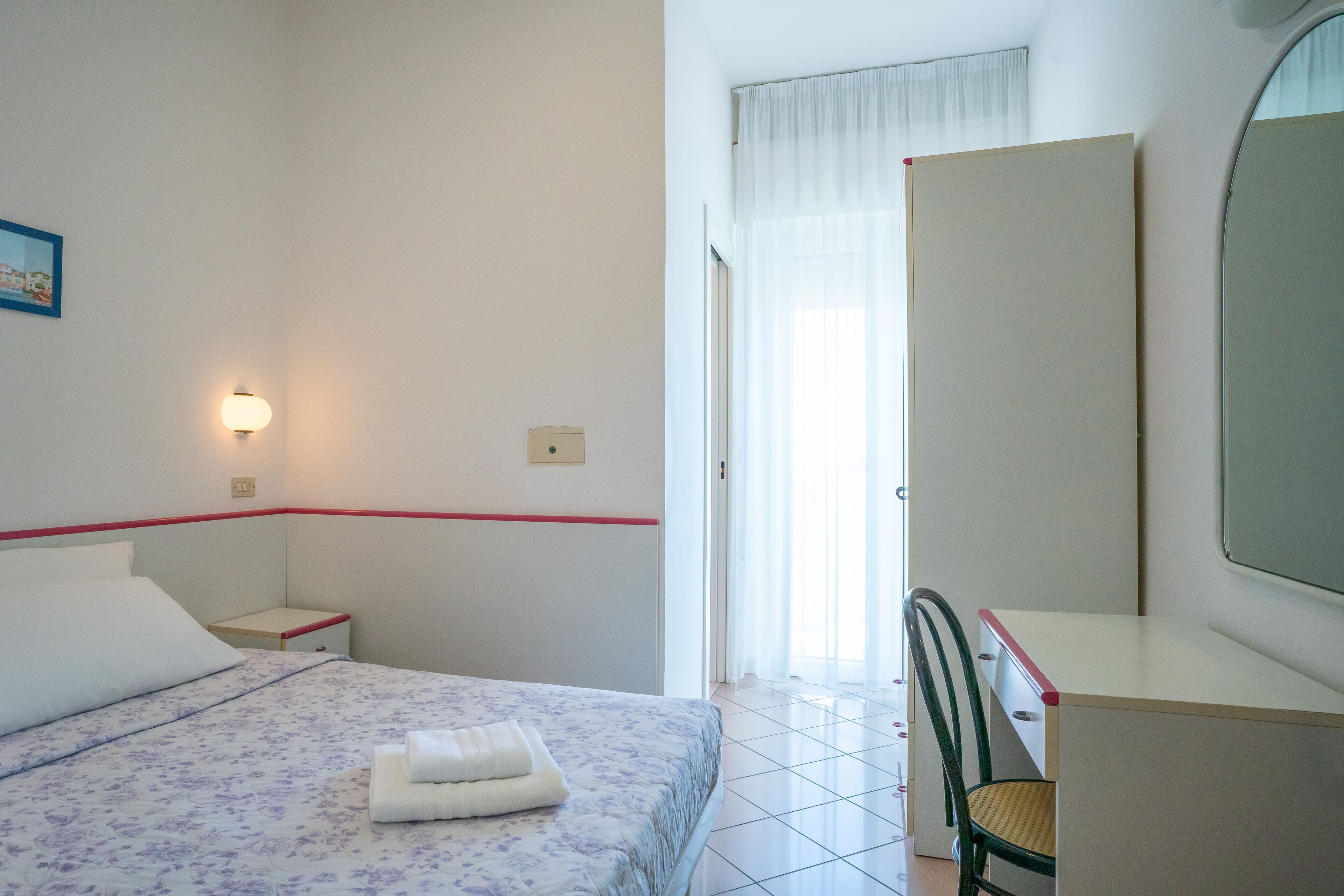 Una camera da letto con un letto, un comodino, una scrivania e una sedia.