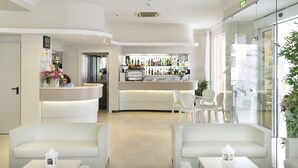 Un moderno vestíbulo de hotel con mostrador de recepción, zona de estar y bar.