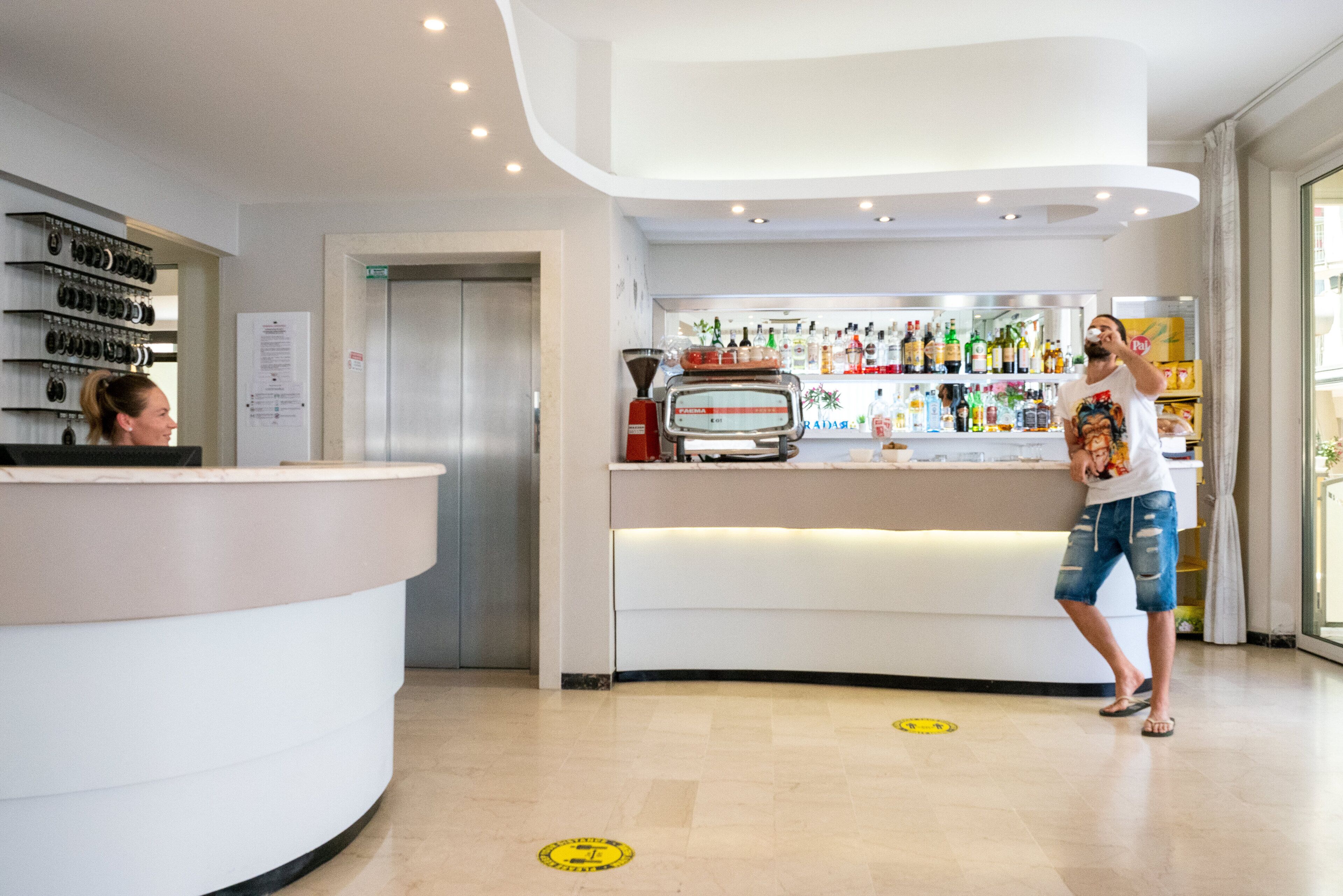 Een moderne receptie met een gebogen balie, een koffieapparaat en diverse drankjes.