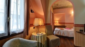 A hotel room with a bed, a small table with a lamp, a chair, and a view through an arched doorway. - Hotel Due Mondi (Turin)