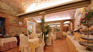 A restaurant with brick walls, white chairs, and tables set for dining. - Hotel Due Mondi (Turin)