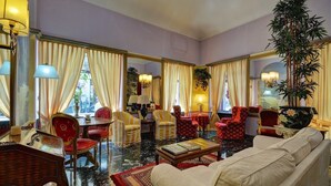 A spacious living room with a sofa, armchairs, and a dining table. - Hotel Due Mondi (Turin)