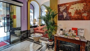 A lobby with a marble floor, a reception desk with brochures, a world map, and a sofa with a plant. - Hotel Due Mondi (Turin)