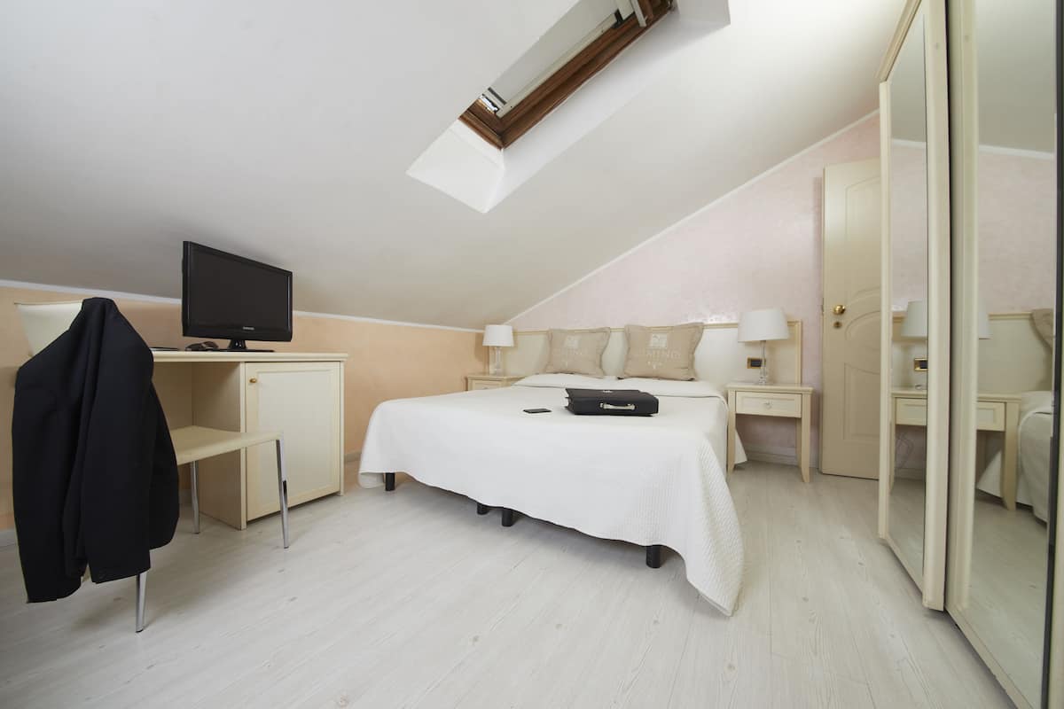 A bedroom with a bed, a desk, a chair, a television, and a wardrobe.