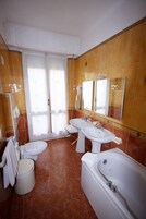 Un bagno con due lavandini, un water, una vasca e uno specchio grande.
