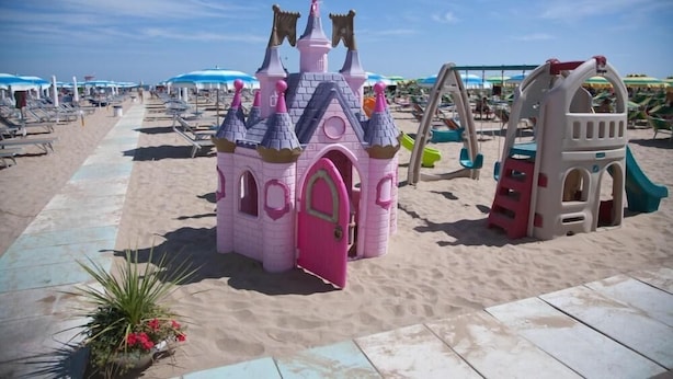A beach with a pink castle play structure and a slide. - Hotel Vienna Ostenda (Rimini)