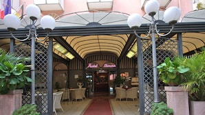 A hotel entrance with a red carpet, outdoor seating, and potted plants. - Hotel Vienna Ostenda (Rimini)