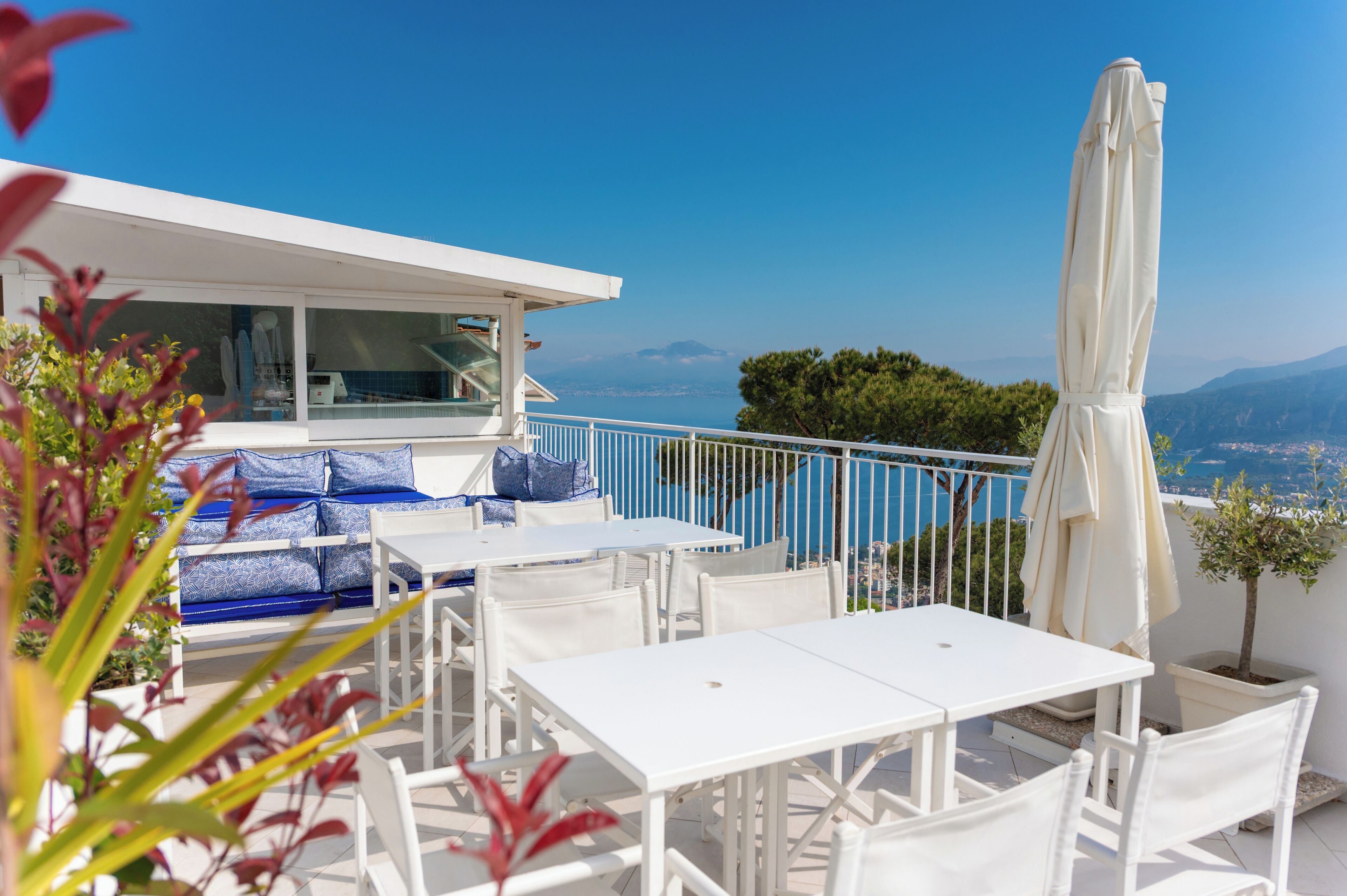 Eine Terrasse mit weißer Möbel, einem Pool und Blick auf das Meer und die Berge.