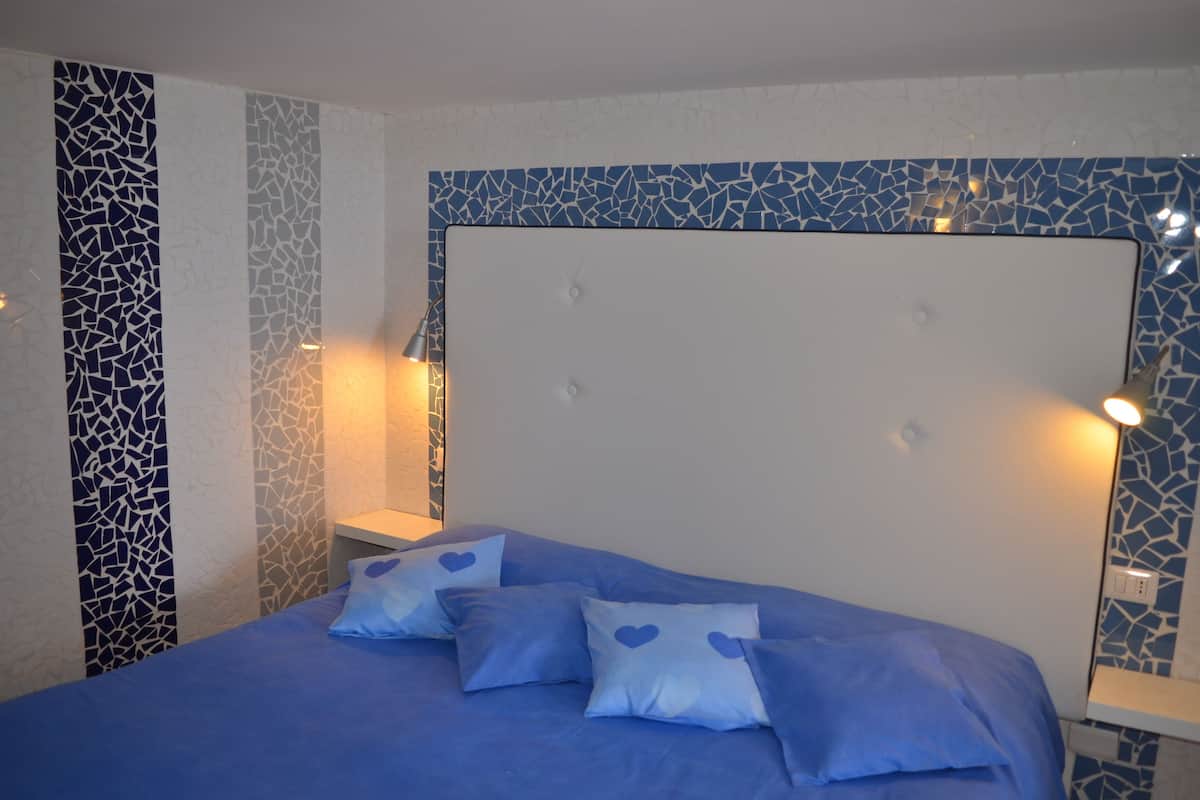 A bedroom with a bed, pillows, and bedside lamps.