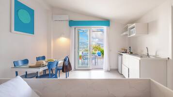 Un espacio habitable compacto con comedor, kitchenette y puerta corrediza de vidrio que da a un patio exterior.