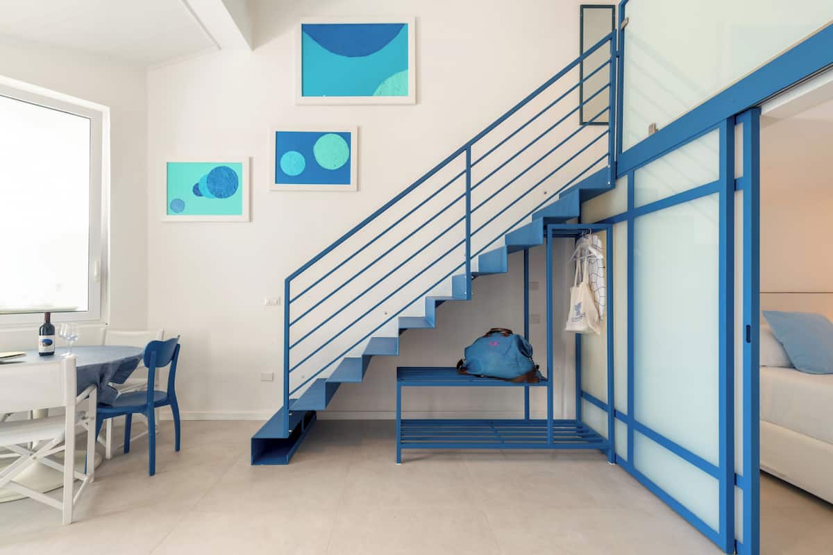 A modern room with a staircase, a dining area, and artwork on the walls.