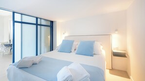 A modern hotel room with a large bed, two pillows, a bedside table, and a view of a dining area. - Le Terrazze (Sorrento)
