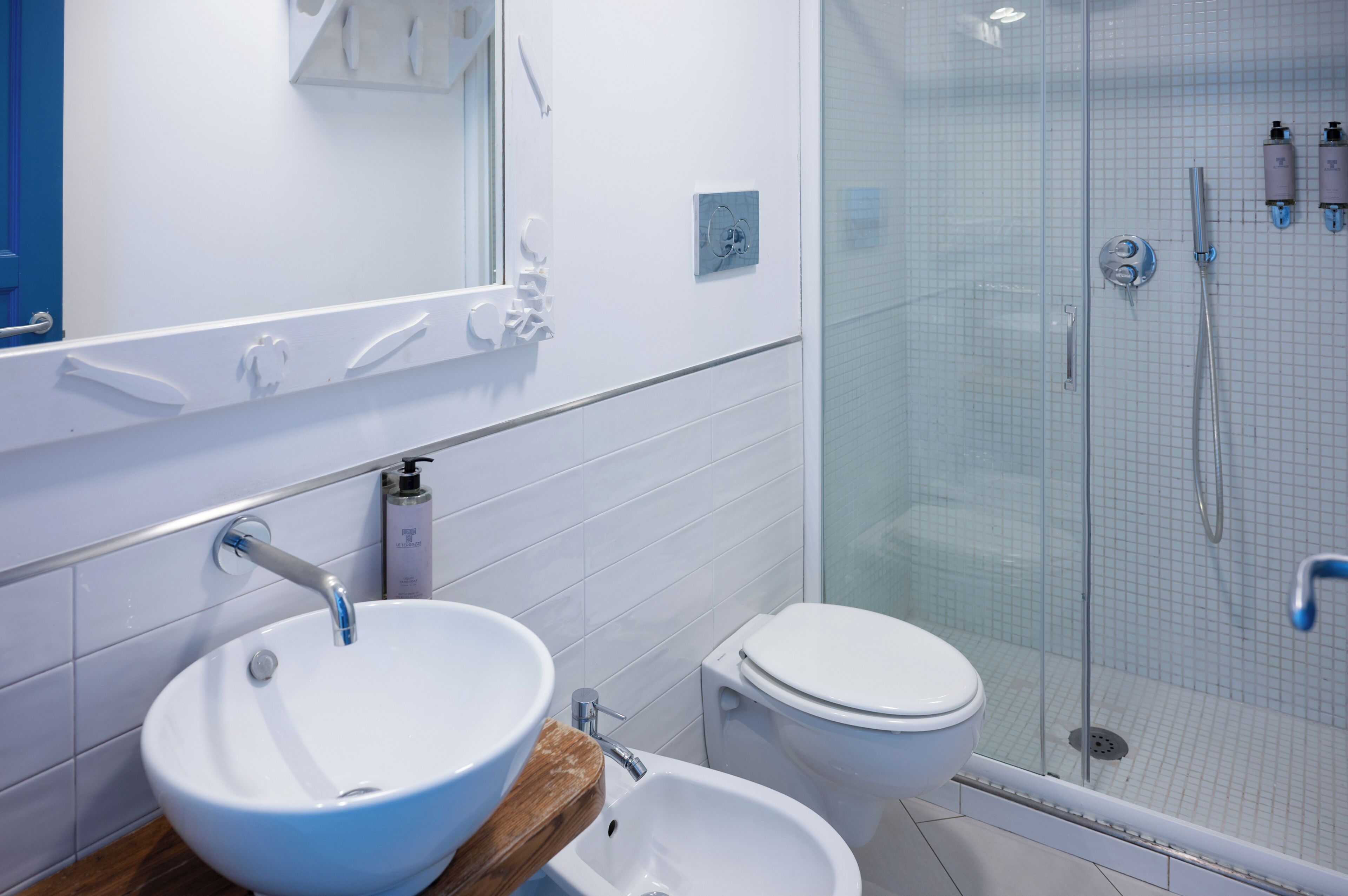 Une salle de bain avec un lavabo blanc, des toilettes et une douche séparée par une paroi en verre.