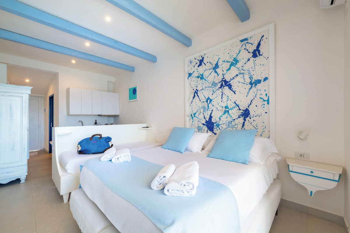 A hotel room with a bed, a bathroom, and a large abstract painting on the wall.