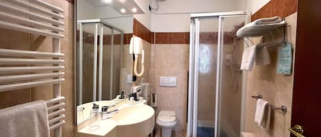 A modern bathroom with a large mirror, a sink, a toilet, and a shower area.