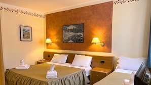 A hotel room with two beds, a desk, a TV, and two wall-mounted lamps. - Hotel Susa (Susa)