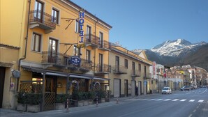 A hotel with balconies, a sign for a restaurant, and a mountain in the background. - Hotel Susa (Susa)