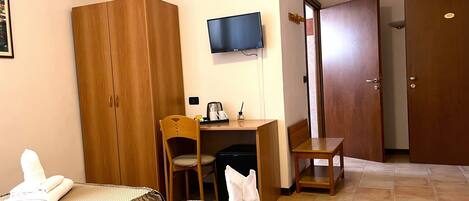 A hotel room with two beds, a desk, a television, and a wardrobe.