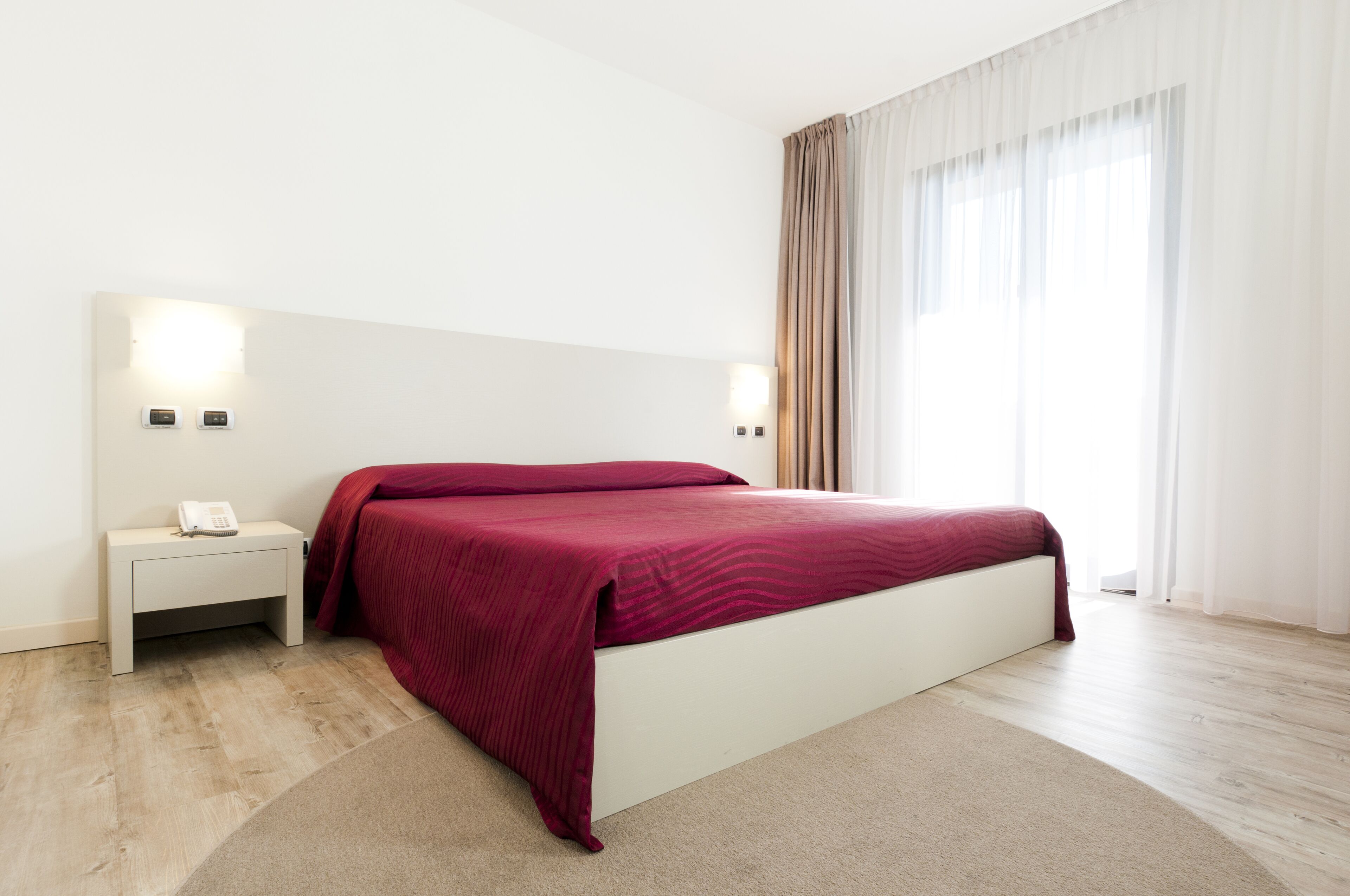Una camera da letto moderna con un letto, comodini e un telefono.