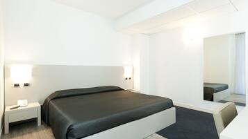 Et moderne hotelværelse med en stor seng, sengeborde og et spejl.