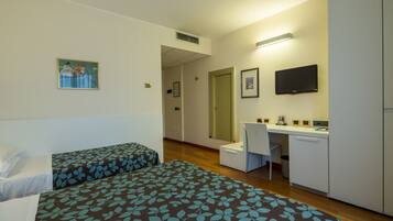 A hotel room with two beds, a desk, a chair, a television, and a mirror.