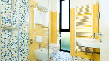 A bathroom with a shower, toilet, sink, and a window.