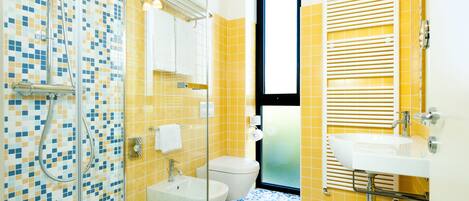 A bathroom with a shower, toilet, sink, and a window.