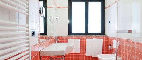 Un baño con un ventanal amplio, un lavabo blanco, una bañera y un inodoro.