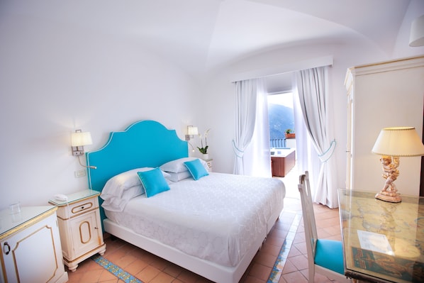 A bedroom with a large bed, a nightstand, a dresser, and a view of the outdoors.