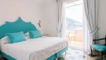 A bedroom with a bed, a chair, and a view of the outdoors.