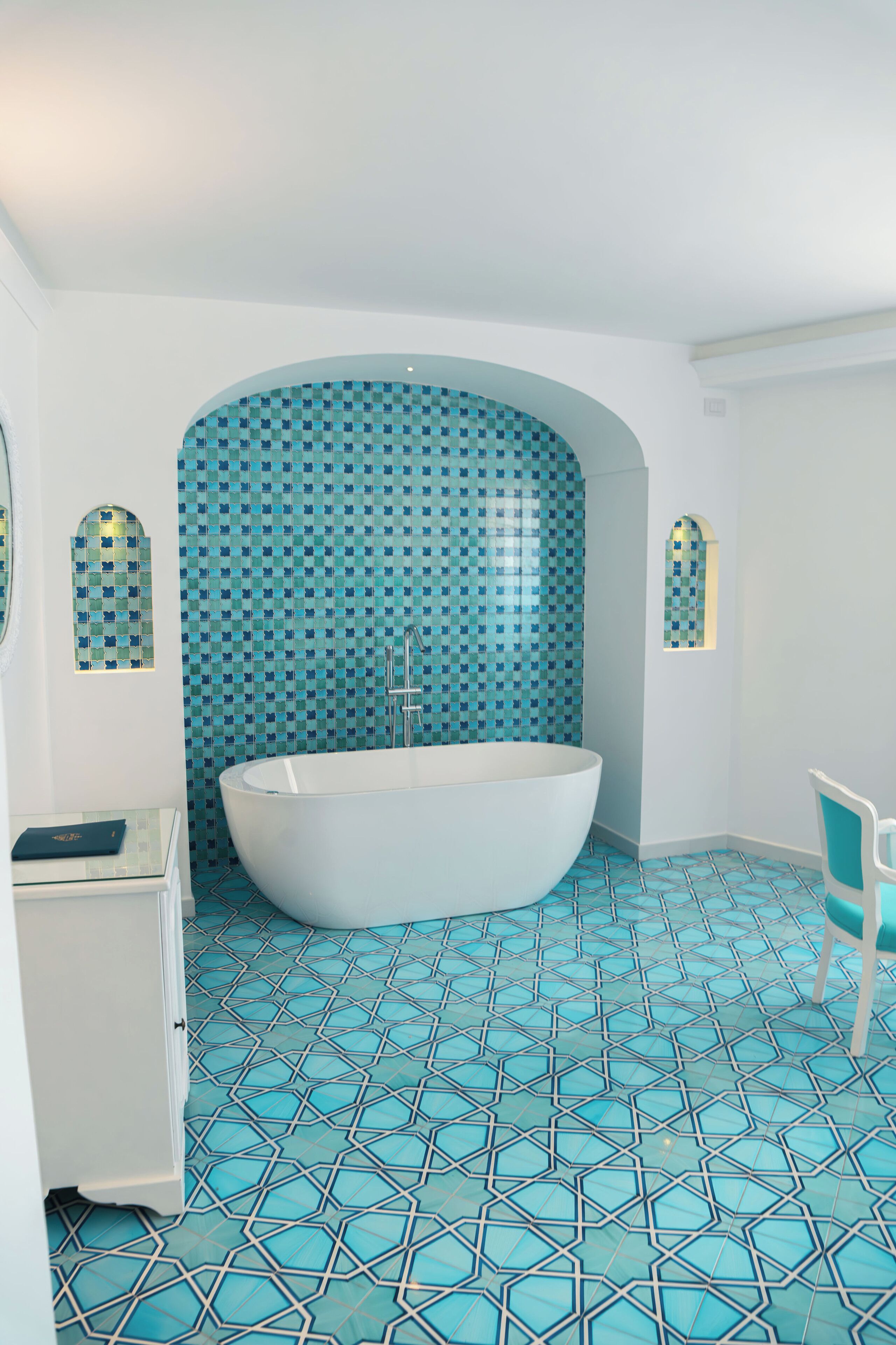 Een badkamer met een vrijstaand bad, een wastafel en een betegelde vloer.